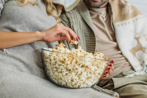 Corte tiro de casal comer pipoca no sofá em casa — Fotografia de Stock