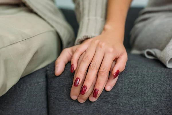 Cropped shot of couple affectionate holding hands while sitting on sofa together — Stock Photo