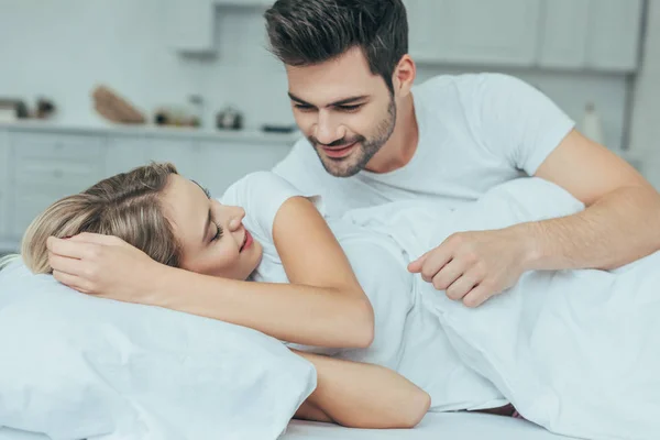 Belo jovem casal abraçando na cama em casa — Fotografia de Stock