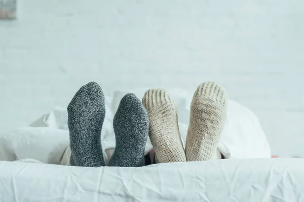 Plan recadré de couple en chaussettes de laine couché dans le lit à la maison — Photo de stock