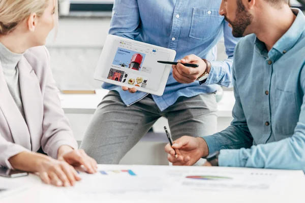 Cropped shot of businessman showing digital tablet with ebay website to colleagues at workplace — Stock Photo