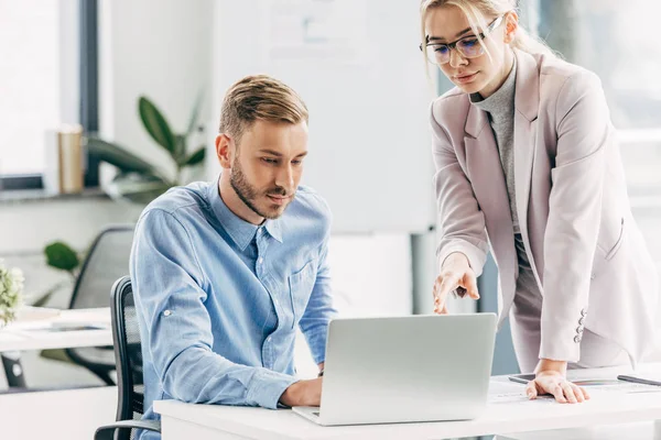 Young businessman and businesswoman working with laptop in office — Stock Photo