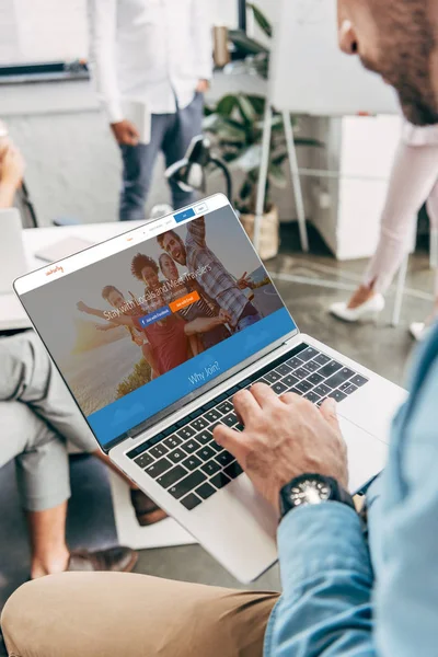 Recortado disparo de joven empresario utilizando el ordenador portátil con couchsurfing sitio web en la pantalla — Stock Photo