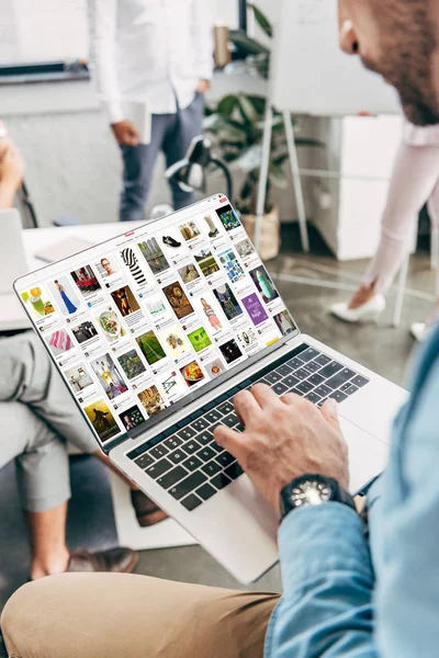 Schnappschuss eines jungen Geschäftsmannes mit Laptop und Pinterest-Website auf dem Bildschirm — Stockfoto