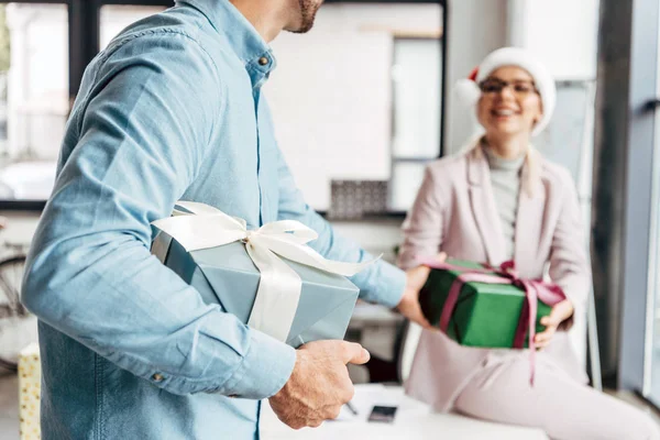 Cropped shot of young businessman presenting christmas gift to female colleague in office — Stock Photo