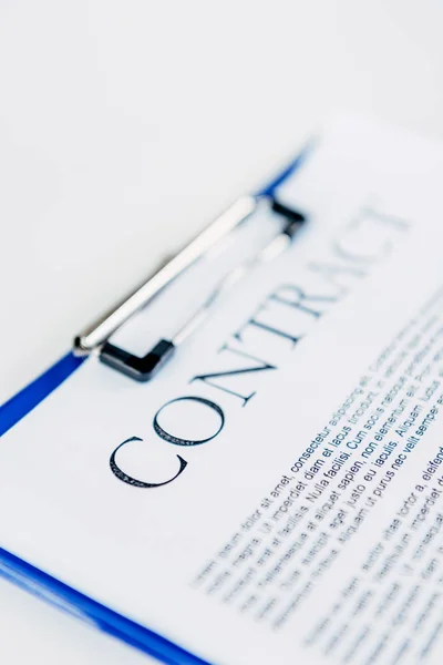 Close-up shot of clipboard with contract on white surface — Stock Photo