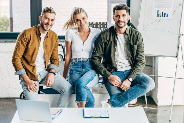 Groupe de jeunes gens d'affaires souriants regardant la caméra ensemble au bureau — Photo de stock