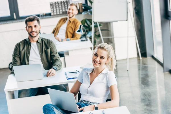 Groupe de jeunes gestionnaires travaillant ensemble dans un bureau ouvert et regardant la caméra — Photo de stock