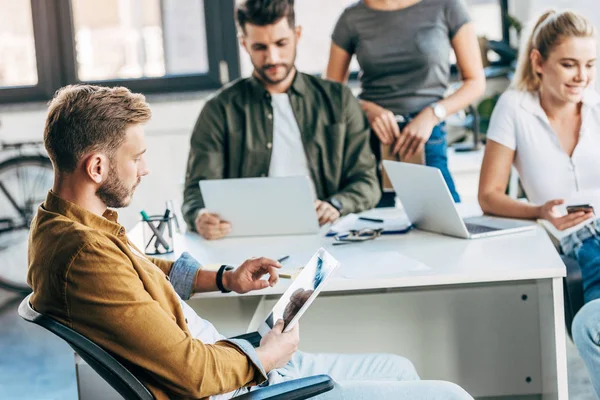 Giovani uomini d'affari occasionali che lavorano con gadget insieme in ufficio — Foto stock