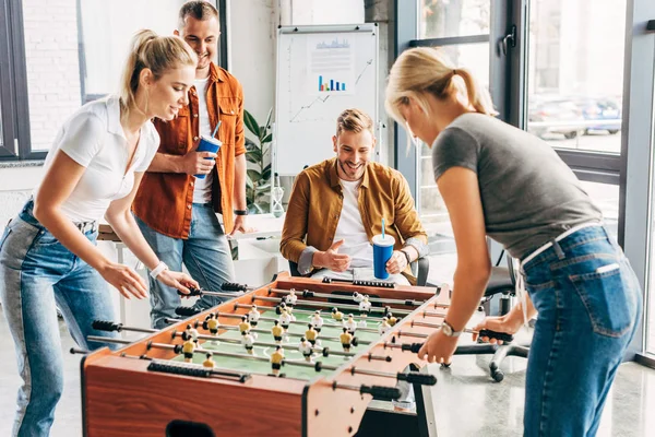 Zufriedene Manager, die im Büro Tischkicker spielen und gemeinsam Spaß haben — Stockfoto