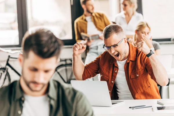 Successful businessman celebrating victory while working on startup at open space office — Stock Photo