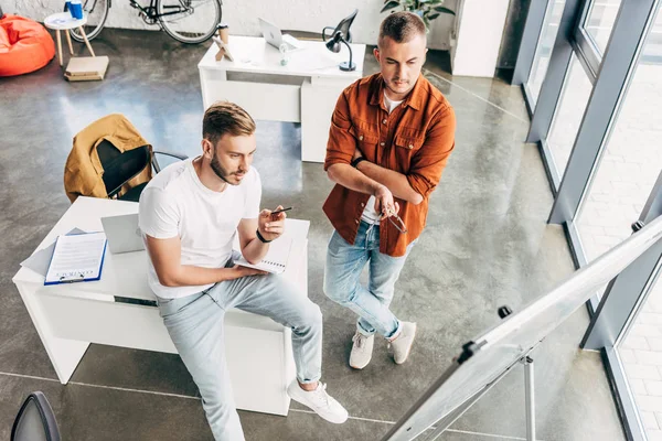 High angle view of young entrepreneurs looking at whiteboard at office — Stock Photo