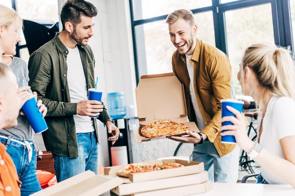 Young successful business people having pizza for lunch together while working on startup at office — Stock Photo
