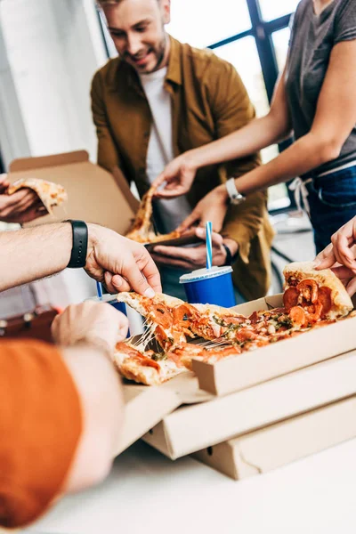 Plan recadré de groupe d'entrepreneurs ayant pizza pour le déjeuner ensemble tout en travaillant sur le démarrage au bureau — Photo de stock