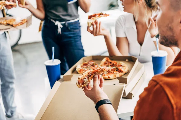 Recortado tiro de grupo de jóvenes empresarios teniendo pizza para el almuerzo juntos mientras se trabaja en la puesta en marcha en la oficina - foto de stock