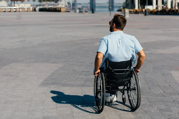 Back view of man in sunglasses using wheelchair on street — Stock Photo