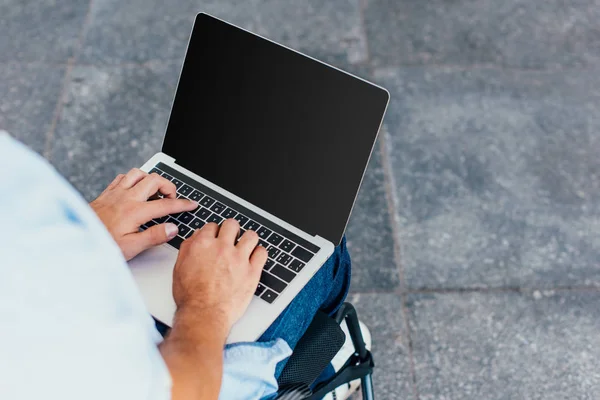 Cropped image of man in wheelchair using laptop with blank screen on street — Stock Photo