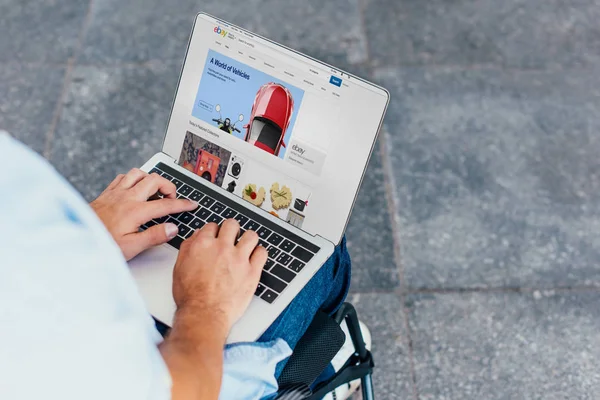 Abgeschnittenes Bild eines Mannes im Rollstuhl mit Laptop beim Online-Einkauf auf ebay-Website auf der Straße — Stockfoto