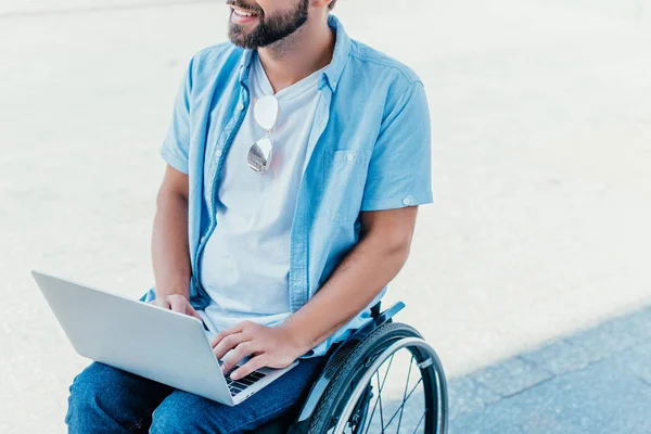 Schnappschuss eines bärtigen Mannes im Rollstuhl mit Laptop auf der Straße — Stockfoto