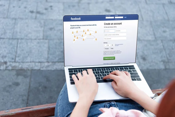 Cropped image of woman using laptop with loaded facebook page on street — Stock Photo