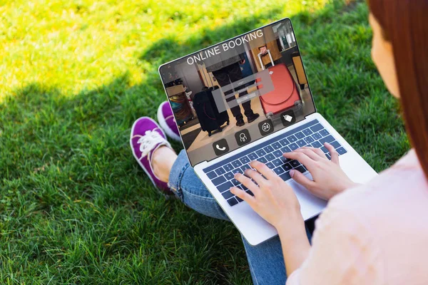 Обрізане зображення жінки за допомогою ноутбука з приладом онлайн-бронювання в парку — стокове фото