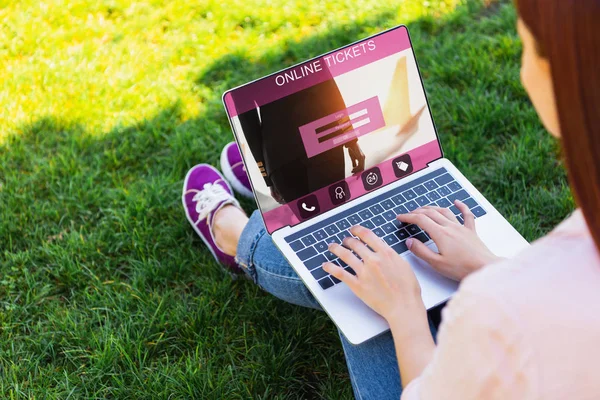 Image recadrée de la femme en utilisant un ordinateur portable avec un appareil de billets en ligne dans le parc — Photo de stock