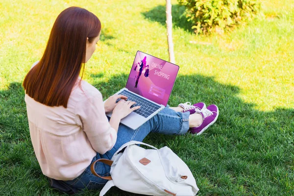 Donna attraente che utilizza il computer portatile con l'apparecchio di shopping online nel parco — Foto stock