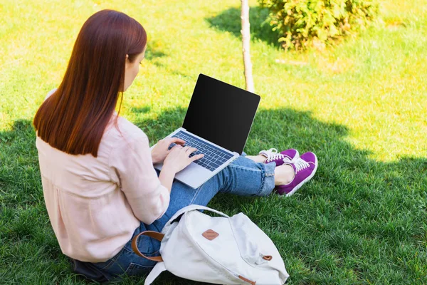 Attractive freelancer using laptop with blank screen in park — Stock Photo