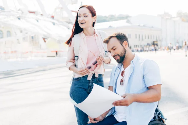 Handsome boyfriend in wheelchair looking at map on street — Stock Photo