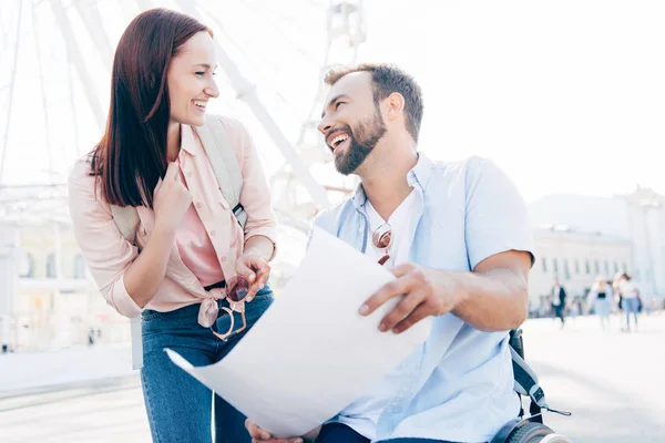 Laughing handsome boyfriend in wheelchair holding map and looking at girlfriend on street — Stock Photo