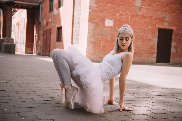 Beautiful elegant ballerina looking down while dancing on street — Stock Photo