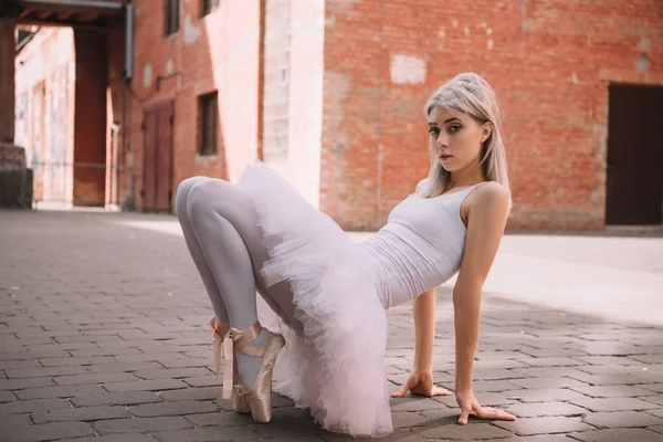 Beautiful elegant ballerina looking at camera while dancing on street — Stock Photo