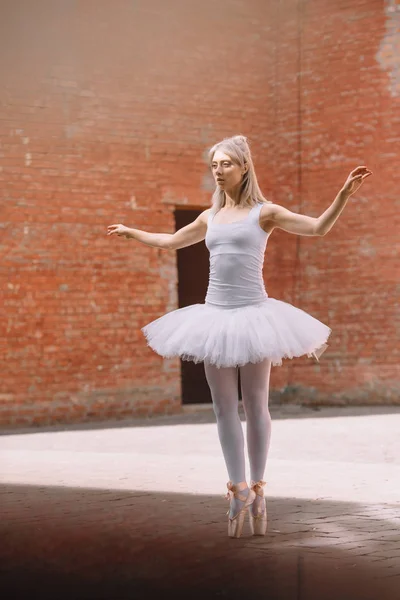 Tutta la lunghezza della giovane ballerina in tutù bianco e scarpe da punta che ballano per strada — Foto stock