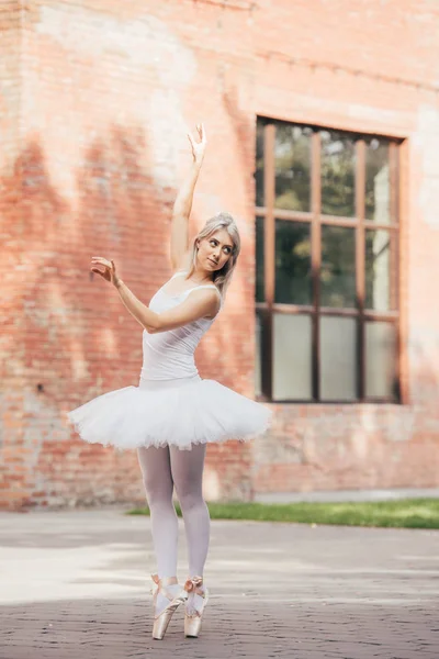 Atractiva bailarina joven sonriente bailando en la calle urbana - foto de stock