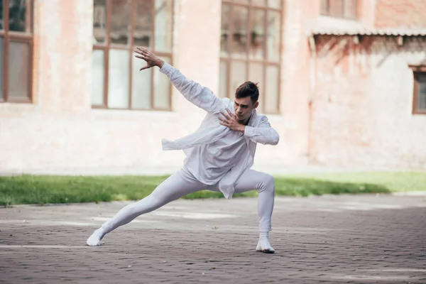 Handsome young man dancer in white clothes dancing on urban city street — Stock Photo
