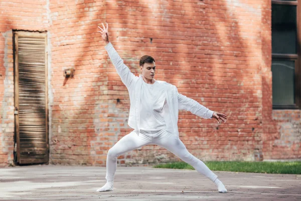 Handsome young man in white clothes dancing on urban street — Stock Photo