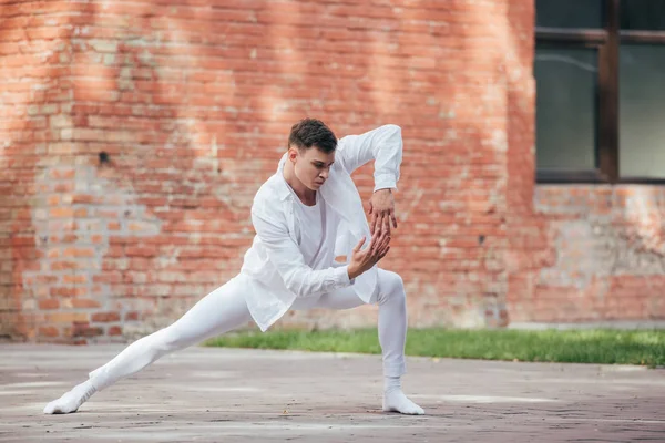 Bonito jovem dançarino masculino em roupas brancas praticando na rua — Fotografia de Stock