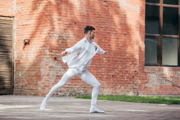 Молодий чоловік танцюрист в білому одязі практикує на вулиці — стокове фото