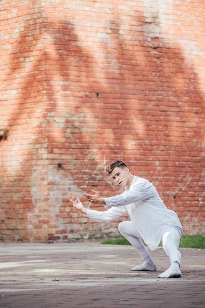 Bonito jovem masculino bailarino balé em branco roupas dançando no urbano rua — Fotografia de Stock