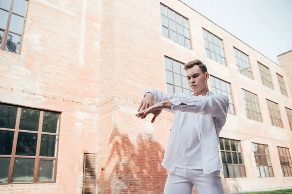 Красива молода чоловіча танцівниця в білому одязі танцює на вулиці — стокове фото