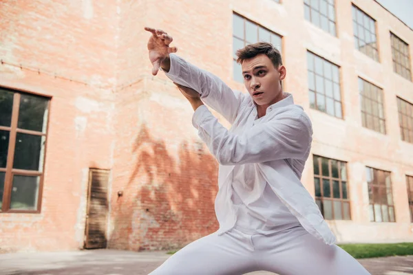 Молодий чоловік танцює в білому одязі танцює на міській вулиці — стокове фото