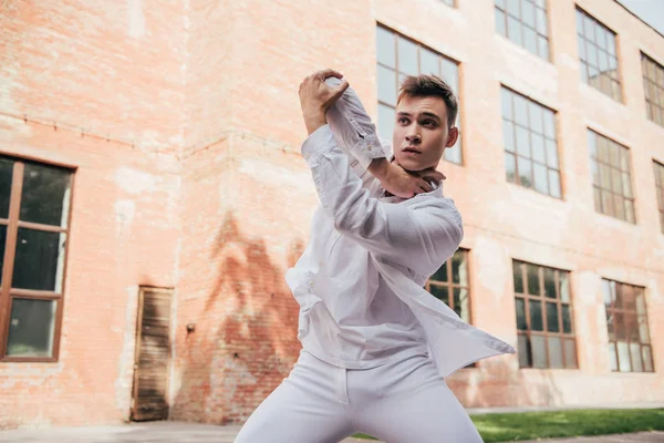 Young man in white clothes dancing on city street — Stock Photo
