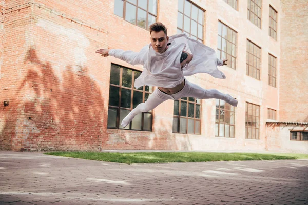 Низкий угол обзора молодой артистки балета в прыжке по городской улице — стоковое фото