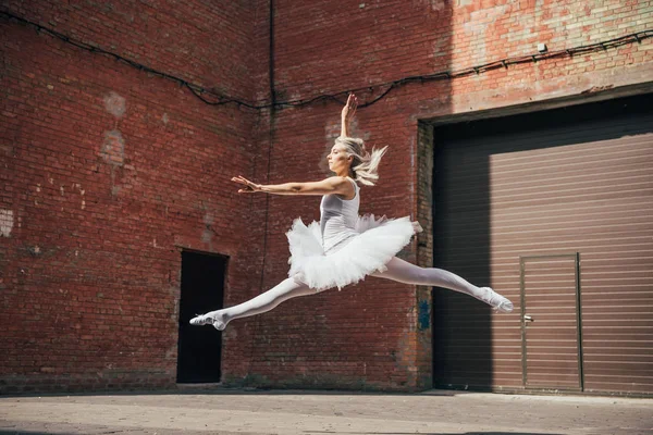 Beautiful young ballerina jumping on urban street — Stock Photo