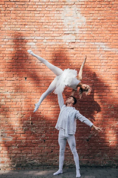 Giovane coppia di ballerini che eseguono danza classica vicino al muro di mattoni — Foto stock