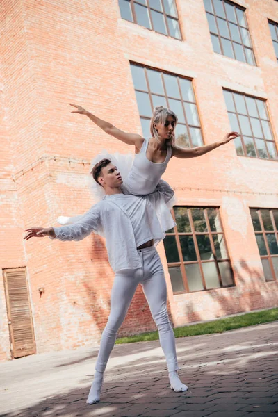 Low angle view of young ballet dancers in white clothes dancing on street — Stock Photo
