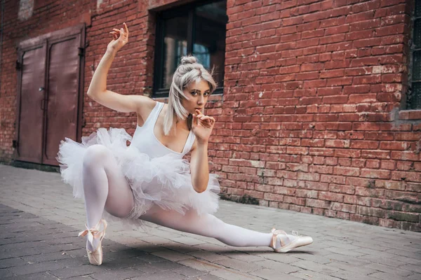 Schöne junge Ballerina schaut in die Kamera, während sie auf der Straße tanzt — Stockfoto