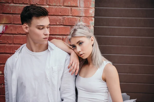 Joven pareja de bailarines de ballet de pie juntos cerca de la pared de ladrillo - foto de stock