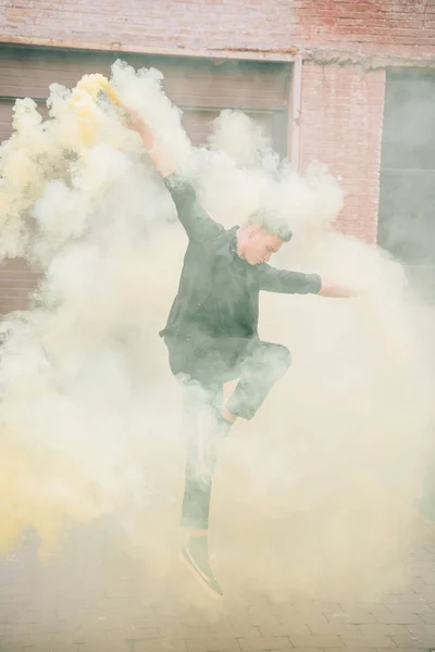 Jeune danseur contemporain masculin sautant en fumée dans la rue urbaine — Photo de stock