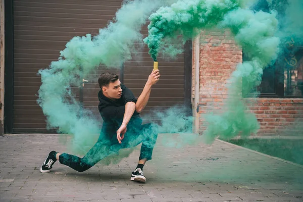 Jovem bonito dançando em fumaça verde na rua urbana da cidade — Fotografia de Stock